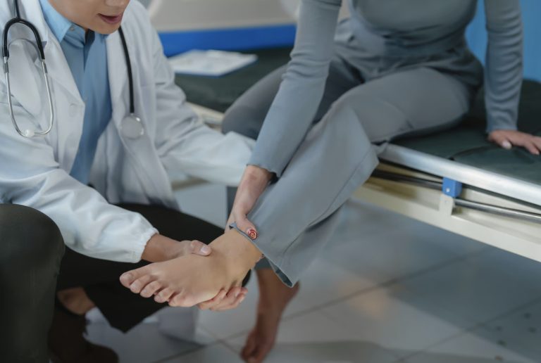A doctor examining a patient's ankle while seated in a clinical setting.