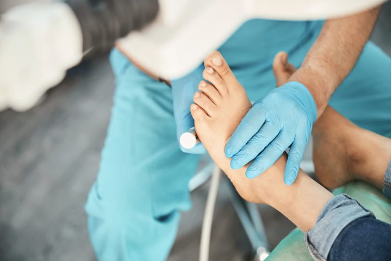 A healthcare professional carefully examining a patient's foot while wearing blue gloves in a clinical setting.