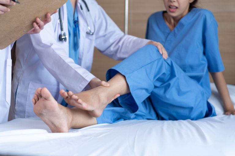 A medical professional examining a patient's ankle during a consultation.
